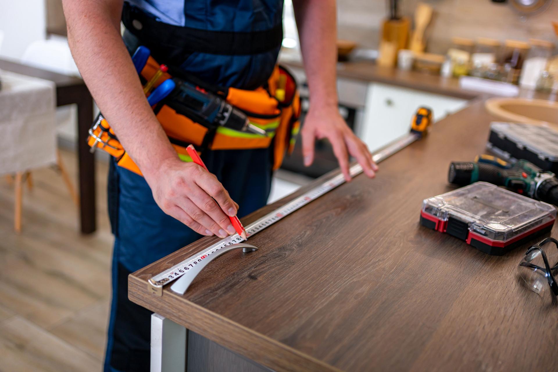 Carpenter measures wooden countertop for precise cutting and installation in kitchen